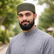 Man wearing grey traditional Islamic dress with prayer cap outdoors
