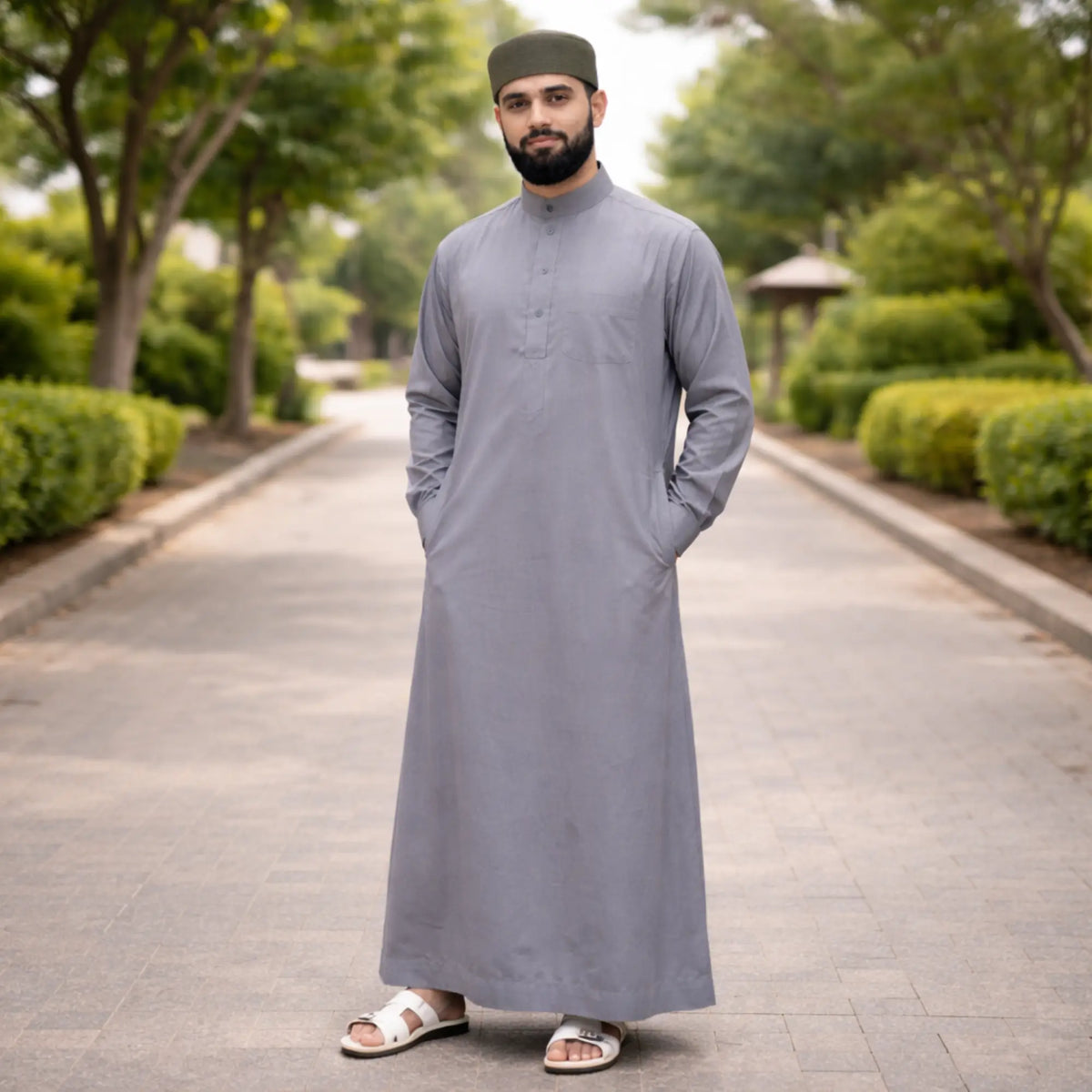 Back view of man in grey Islamic attire with green prayer cap
