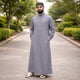 Back view of man in grey Islamic attire with green prayer cap