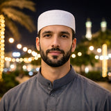 Man wearing white Islamic prayer cap at night
