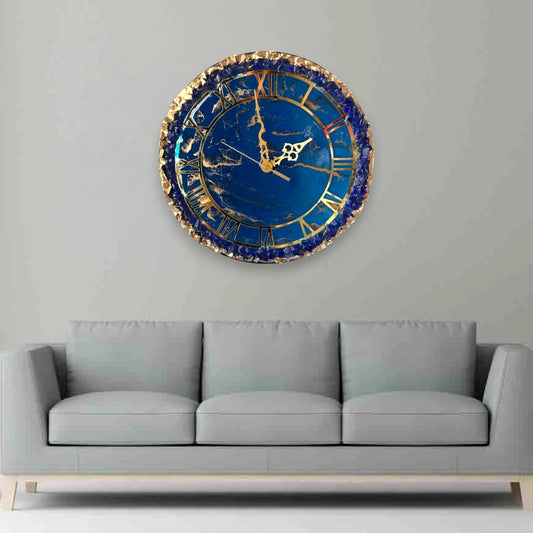 Eternal Blue Elegance Wall Clock with gold detailing and resin finish, displayed above a grey sofa in a modern living room setting.