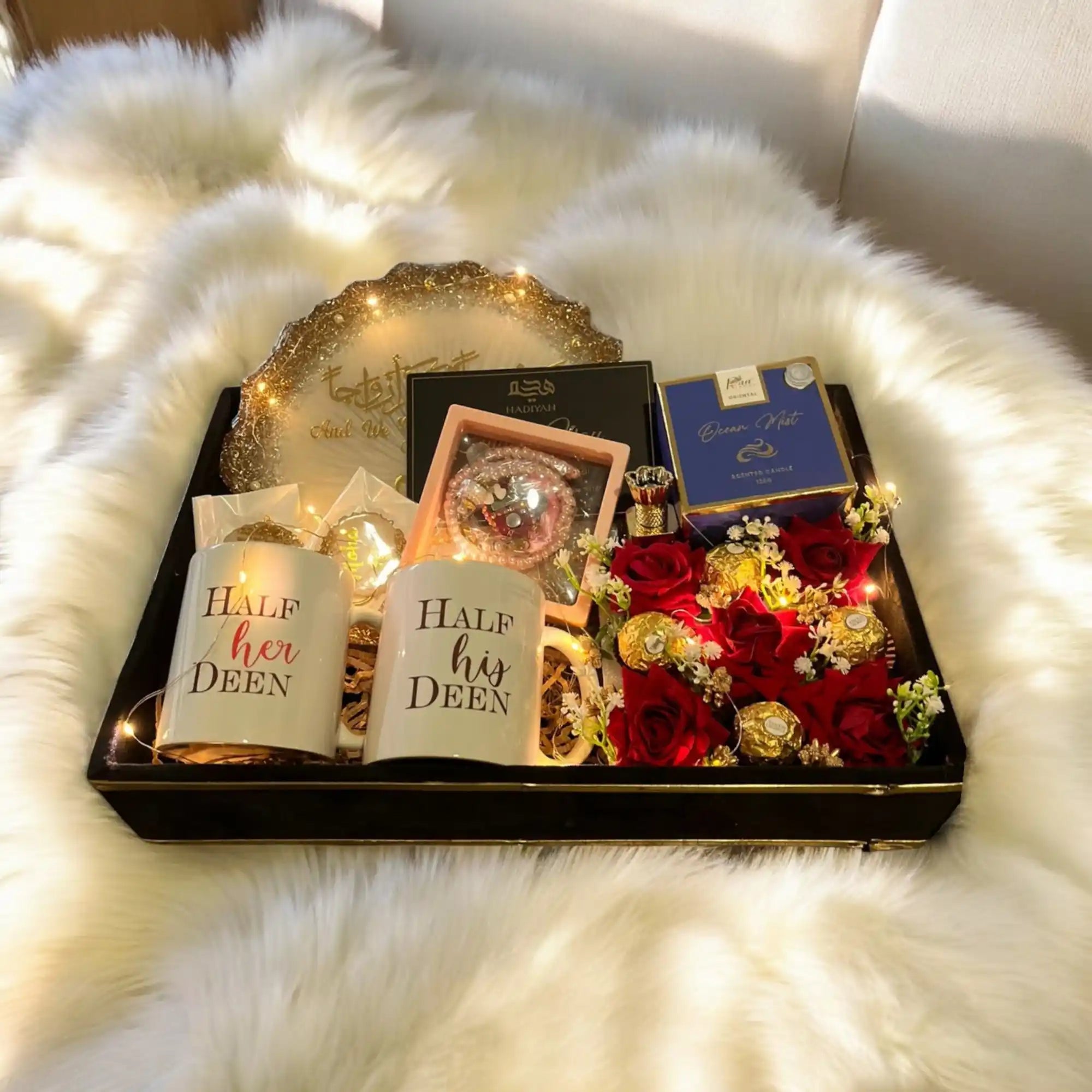 Gift set with candles, flowers, and a box on a fluffy white surface Main image