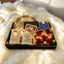 Gift set with candles, flowers, and a box on a fluffy white surface