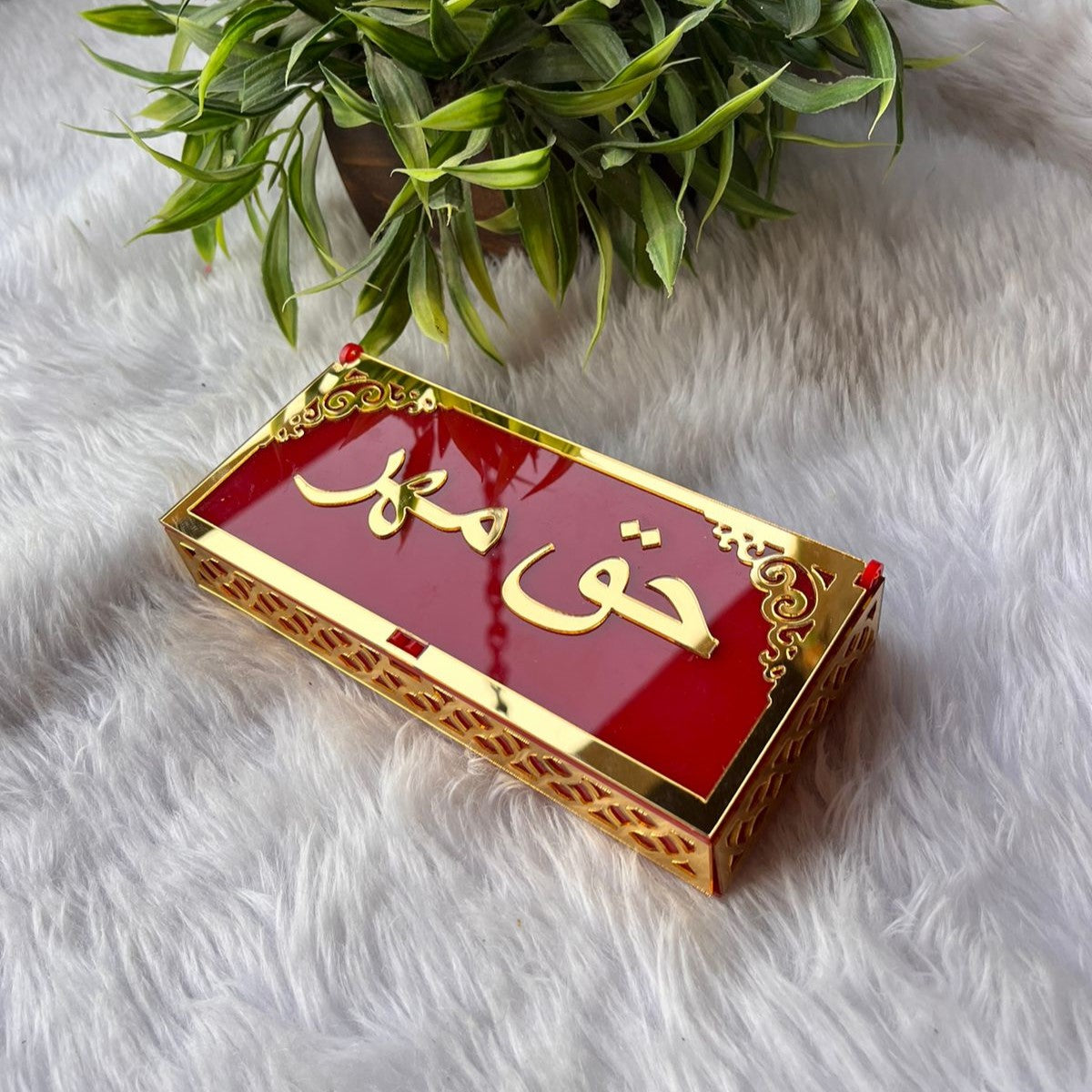 Angled view of red and gold Haqq Mehr envelope with ornate border, used for ceremonial gifting during weddings and Nikah.