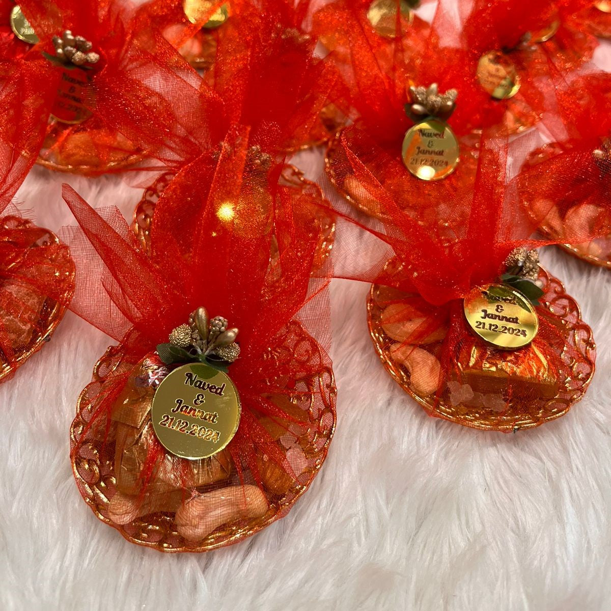 Detailed view of red Mix Dry-Fruit Nikah Favor Gift Trays featuring gold tags and festive red net wrap, ideal for Nikah celebrations.