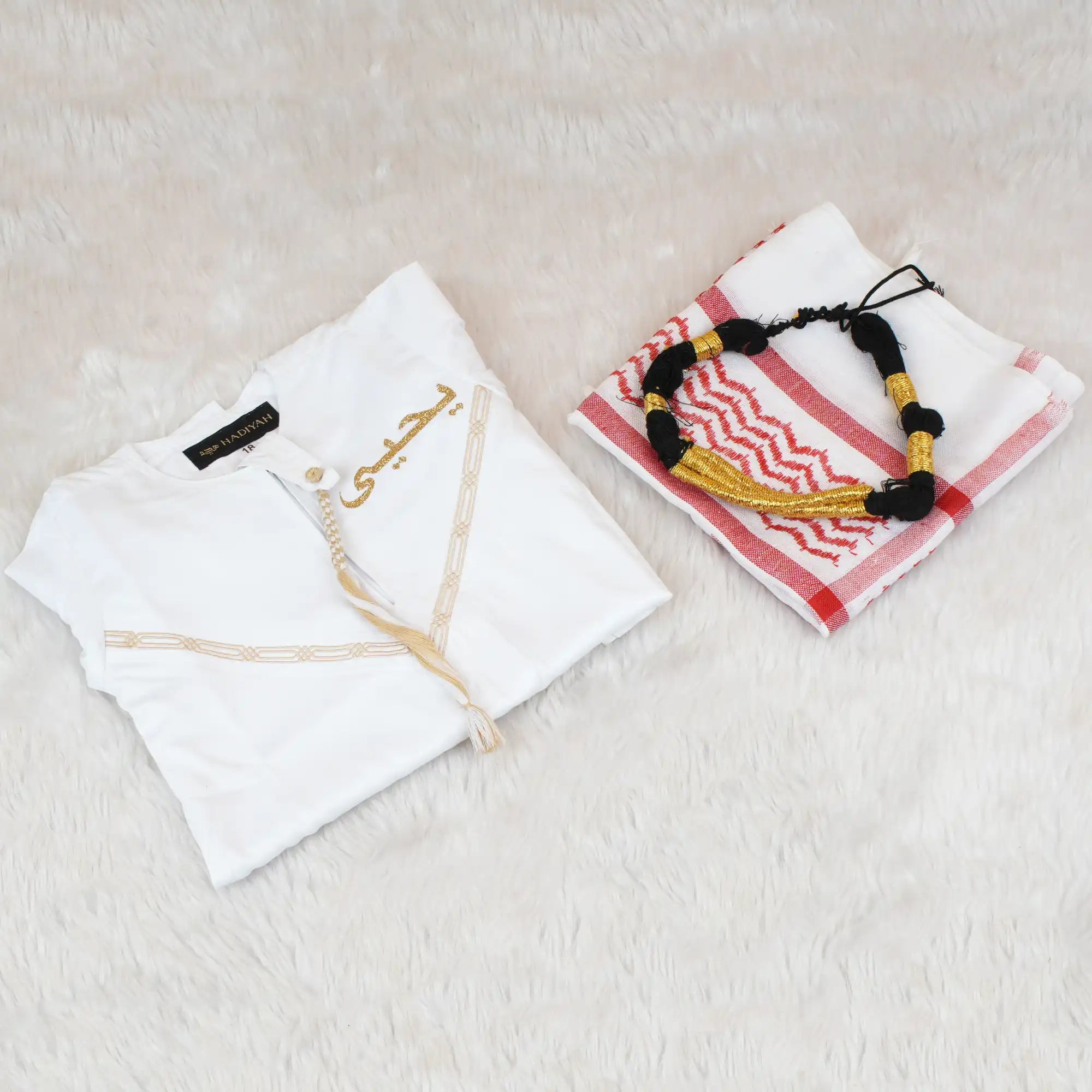 White garment with embroidery and a folded towel with a decorative pattern on a light surface