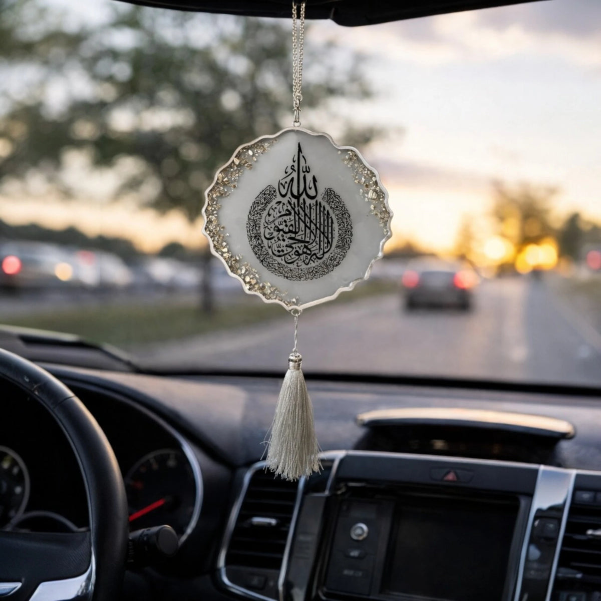 Decorative hanging car ornament with tassel on a car dashboard.