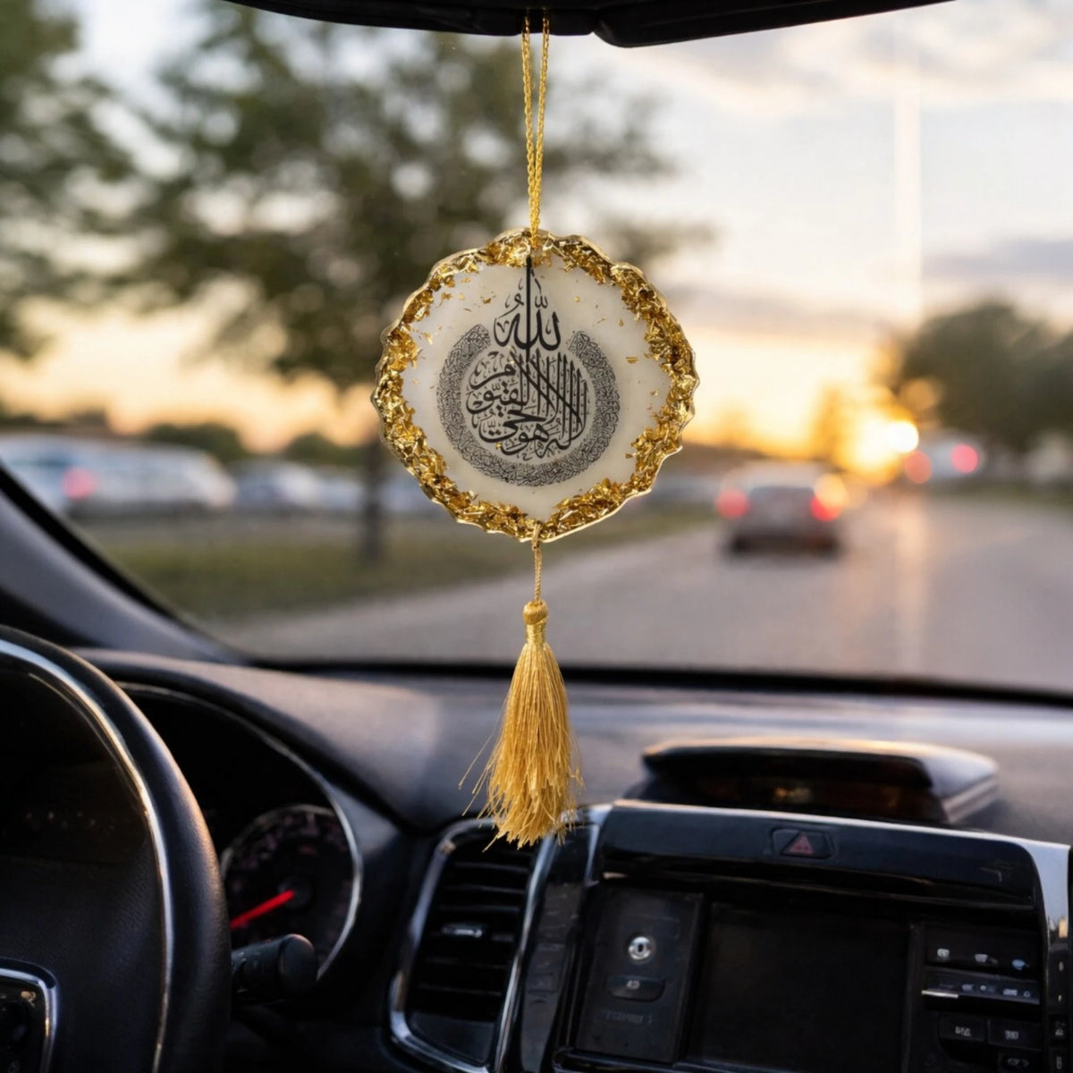Decorative hanging ornament with tassel inside a car during sunset.