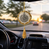 Decorative hanging ornament with tassel inside a car during sunset.