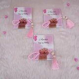 Three pink Little Hands Tasbeeh Keepsakes with personalized cards on soft fur, perfect for Aqiqah and kids' religious gifts.
