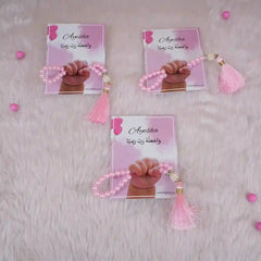 Three pink Little Hands Tasbeeh Keepsakes with personalized cards on soft fur, perfect for Aqiqah and kids' religious gifts.