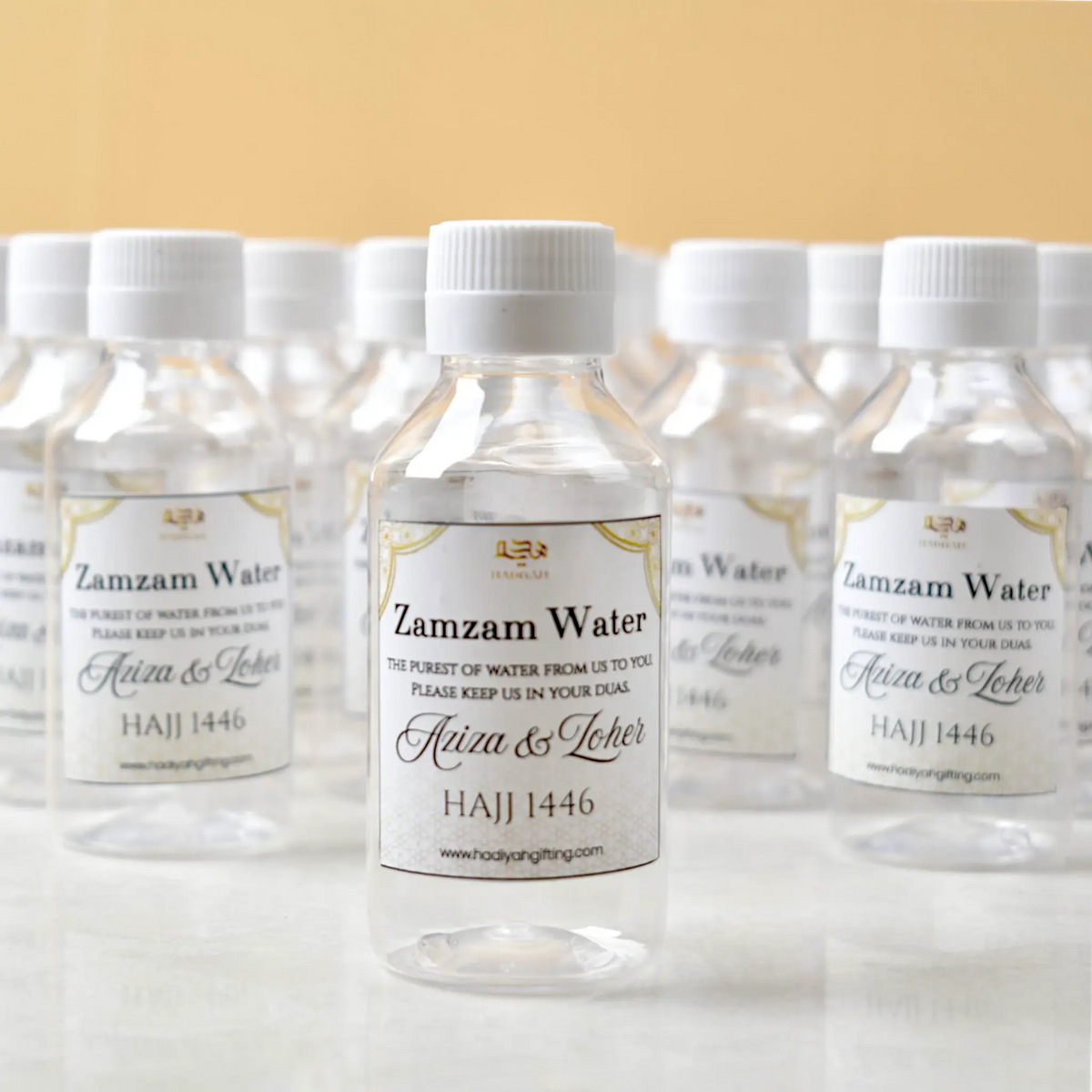 Zamzam Bottles 100ml Pack - Sacred Water Gifts featuring personalized Hajj 1446 labels, ideal for Umrah return gifts and Islamic celebrations.