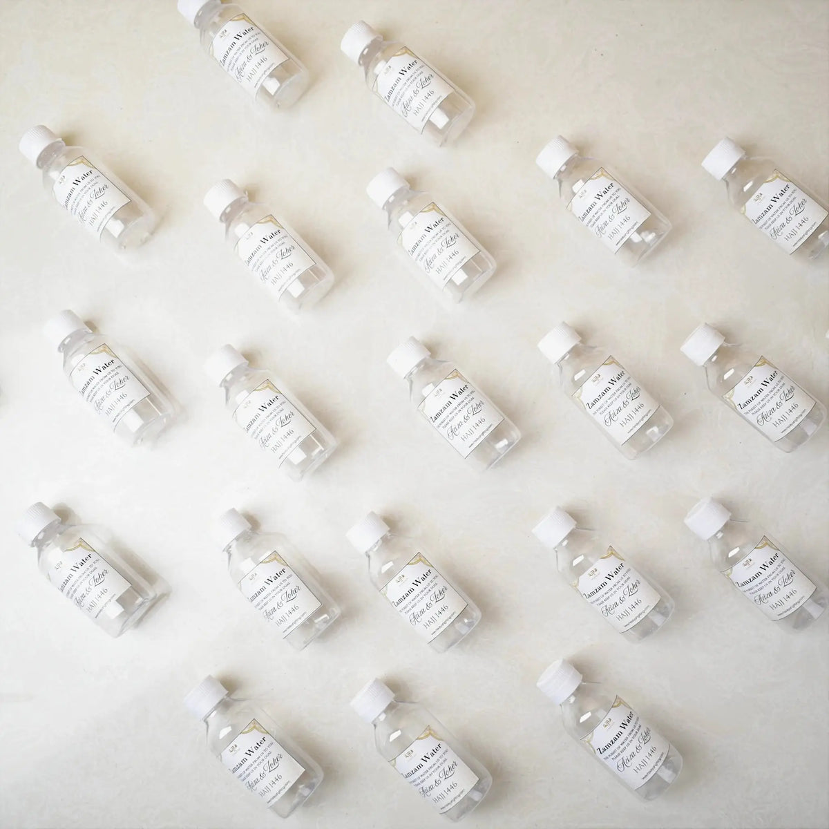 Flat lay of 100ml Zamzam water bottles with custom labels, ideal for aqeeqah, Islamic gift delivery, and Hajj Umrah return favors.