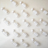 Flat lay of 100ml Zamzam water bottles with custom labels, ideal for aqeeqah, Islamic gift delivery, and Hajj Umrah return favors.