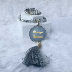 Bracelet with a gray pendant and tassel on a white background