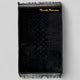 Black prayer mat with intricate design and 'Huzaija Rameeza' branding on a light gray background