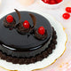 Yummylicious Chocolate Cake - Order Dessert Online | Rich Indulgence, close-up of glossy chocolate cake with piped frosting, cherries, and decorative chocolate pieces.