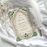 Flat lay of Emerald Nikah Nama Frame on white satin with feather and dried flowers, showcasing elegant Islamic wedding keepsake.