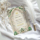 Flat lay of Emerald Nikah Nama Frame on white satin with feather and dried flowers, showcasing elegant Islamic wedding keepsake.