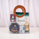 The green-themed Imaan Play & Pray Kids Hamper fully assembled inside a clear PVC bag with round brown handles. A green prayer mat, Basic Duas book, green digital tasbeeh, golden lantern, cookie tin, and crayons are visibly neatly packed inside.