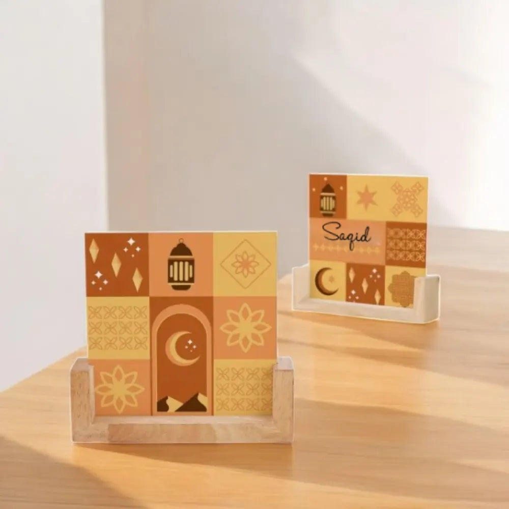 Two decorative cards with patterns and 'Saqid' text on a wooden stand against a light background.