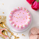 Soft Vanilla Cake - Simple Delights featuring smooth pink icing, daisy-like cream decorations, and golden pearls. Perfect for anniversaries or celebrations.