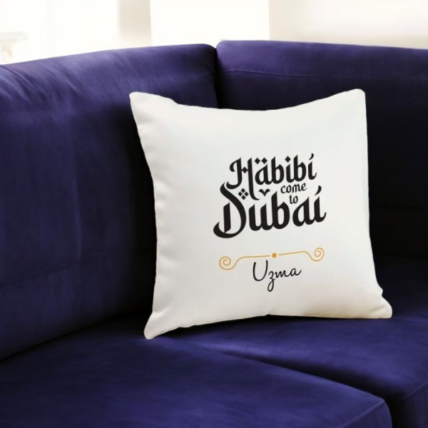 Personalized Habibi Come to Dubai Cushion featuring name Uzma, displayed on a dark blue couch. Perfect for romantic or festive gifting.