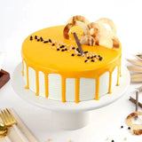 Indulgent Butterscotch Cake - Premium with creamy caramel glaze, chocolate chips, and decorative toppings on a white cake stand.