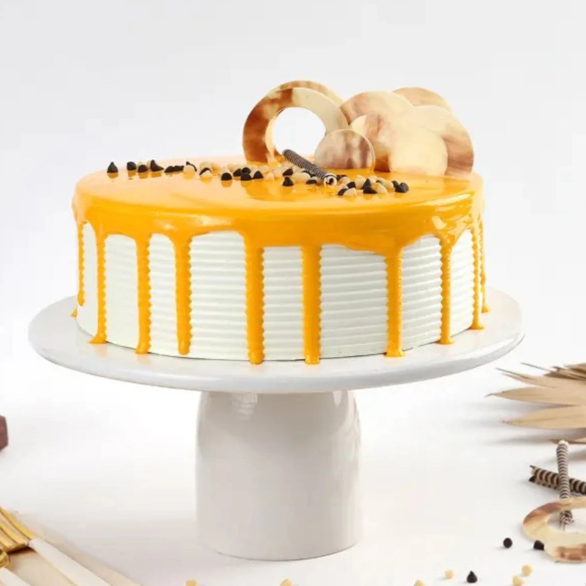 Round creamy butterscotch cake with caramel drip, layered sponge, and artistic chocolate garnishes, perfect for dessert lovers and festive occasions.