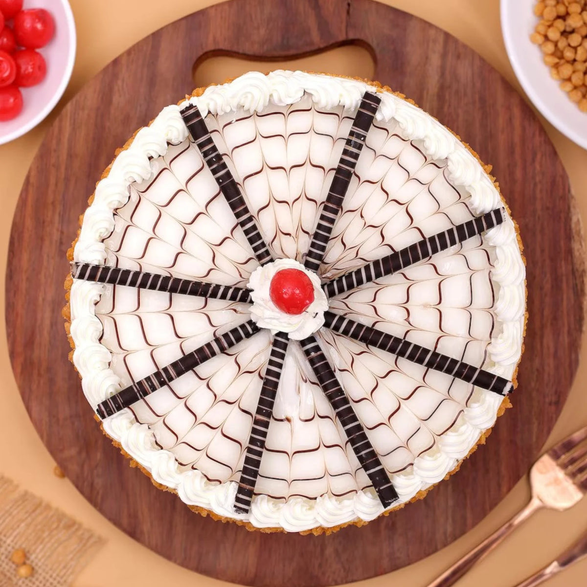 Top view of Butterscotch Cake Online featuring cream web design, chocolate sticks, cherry center, and crunchy caramel bits. Ideal for celebrations.
