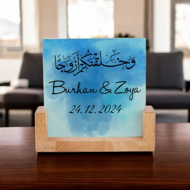Decorative plaque with Arabic calligraphy and names on a wooden stand in a blurred indoor setting