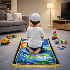 Kids Prayer Mat - Personalized Mat | Janamaz for Kids featuring a boy praying on a vibrant airplane and Earth-themed mat in a cozy indoor setting.