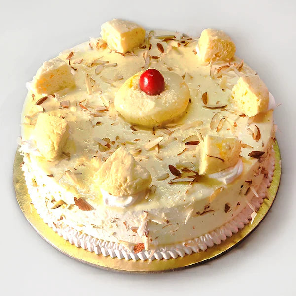 Super Rasmalai Cake topped with rasmalai pieces, cherry, and almond slivers on a golden base. Buy Rasmalai Cake online for celebrations. Main image