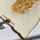 Close-up of a white ceramic plate with gold glitter on a light background