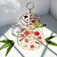 Three-tiered decorative tray with floral design on a white surface with fern leaves.