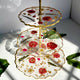 Three-tiered decorative cake stand with floral design on a white surface.