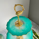 Decorative item with gold accents and a green base on a marble surface.