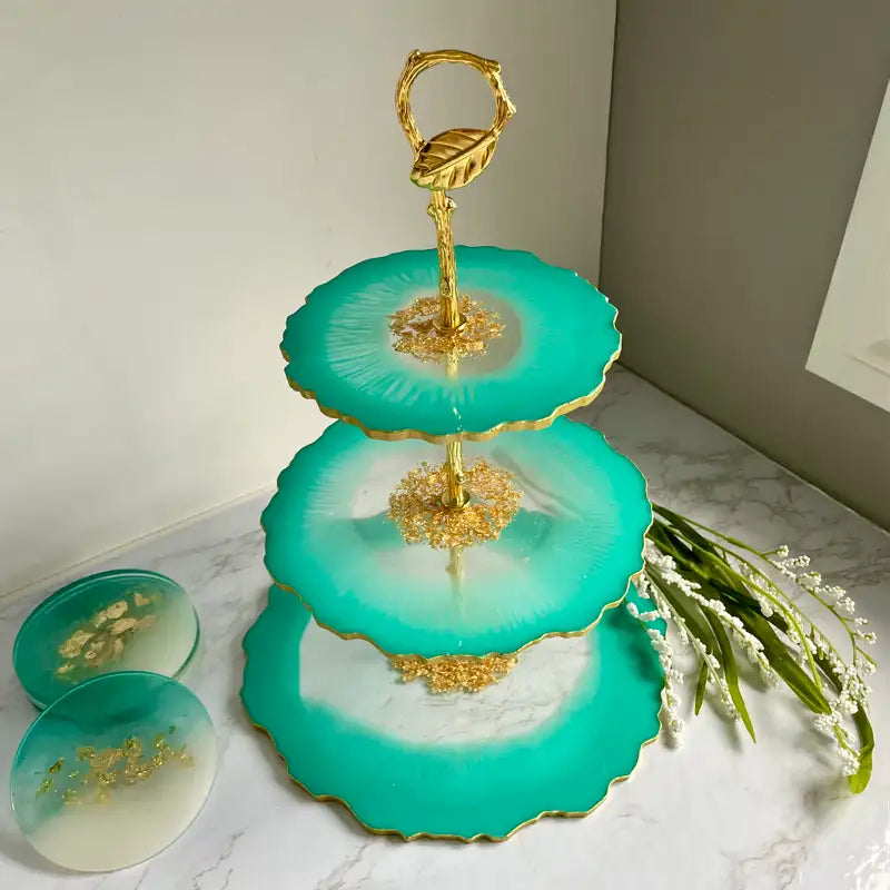 Three-tiered turquoise serving tray with gold accents on a marble surface.