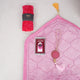 Top-down view of the Little Soul Essentials Hamper contents laid flat on a light surface. It features a light pink quilted kids' prayer mat, a pink digital tasbeeh on a printed card, a matching pink 33-bead tasbeeh with a large agate stone and tassel, and a bright pink rolled prayer makhana secured with a black Hadiyah band.